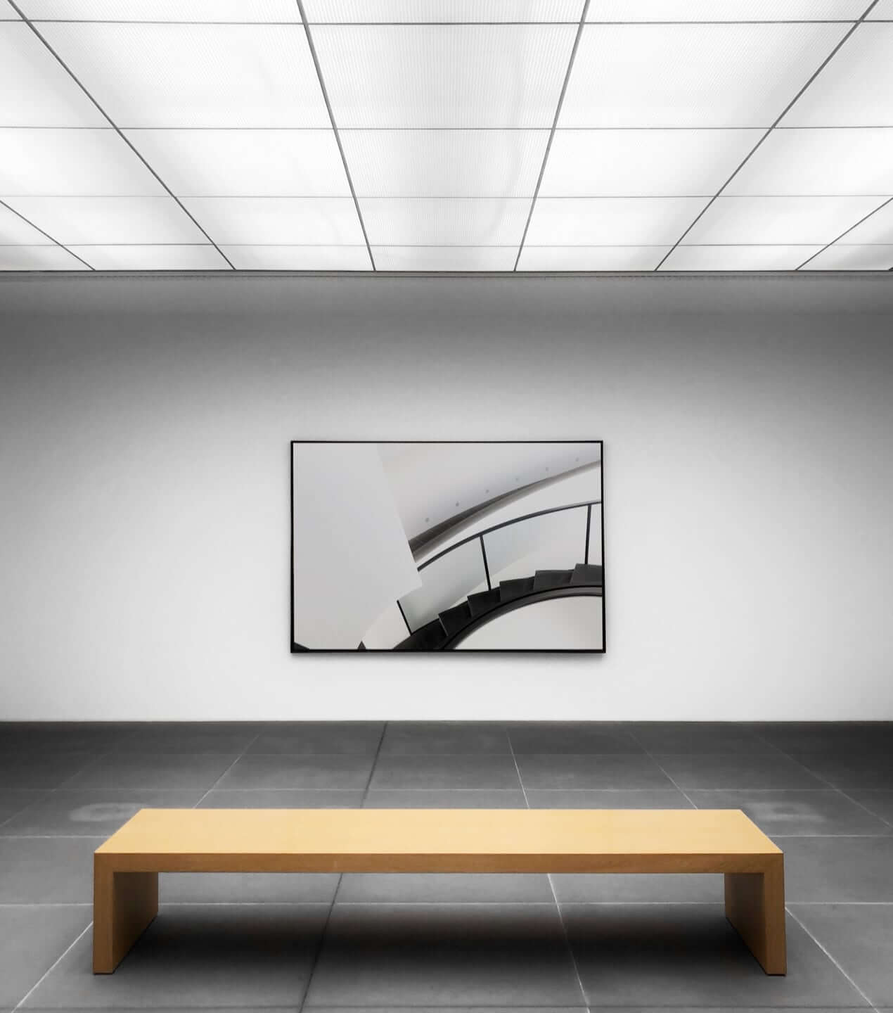 Bench in an empty gallery room with one painting on the wall.